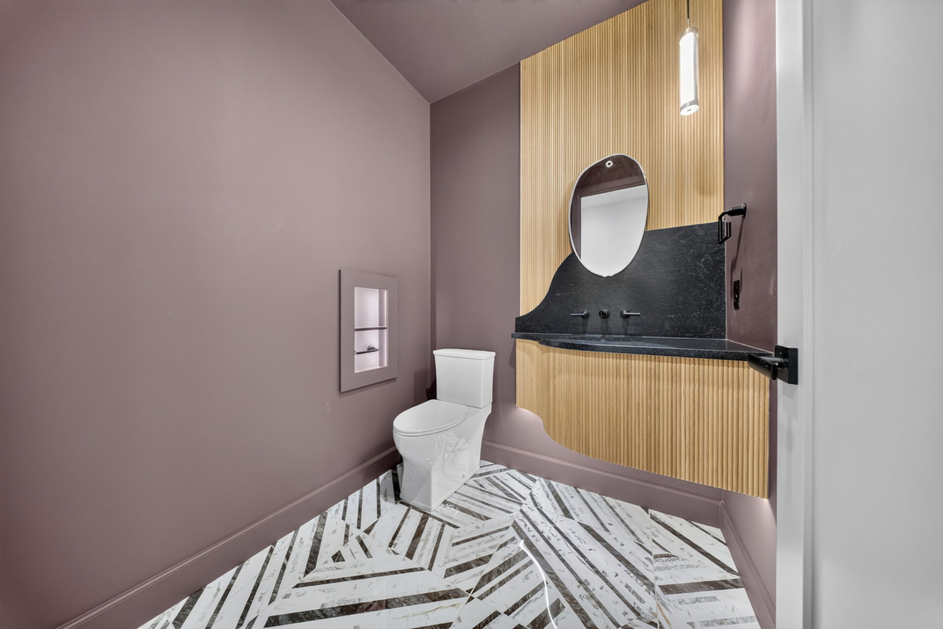Powder room with mauve walls, fluted wood vanity and patterned marble floor tile in a Broken Arrow Oklahoma new build