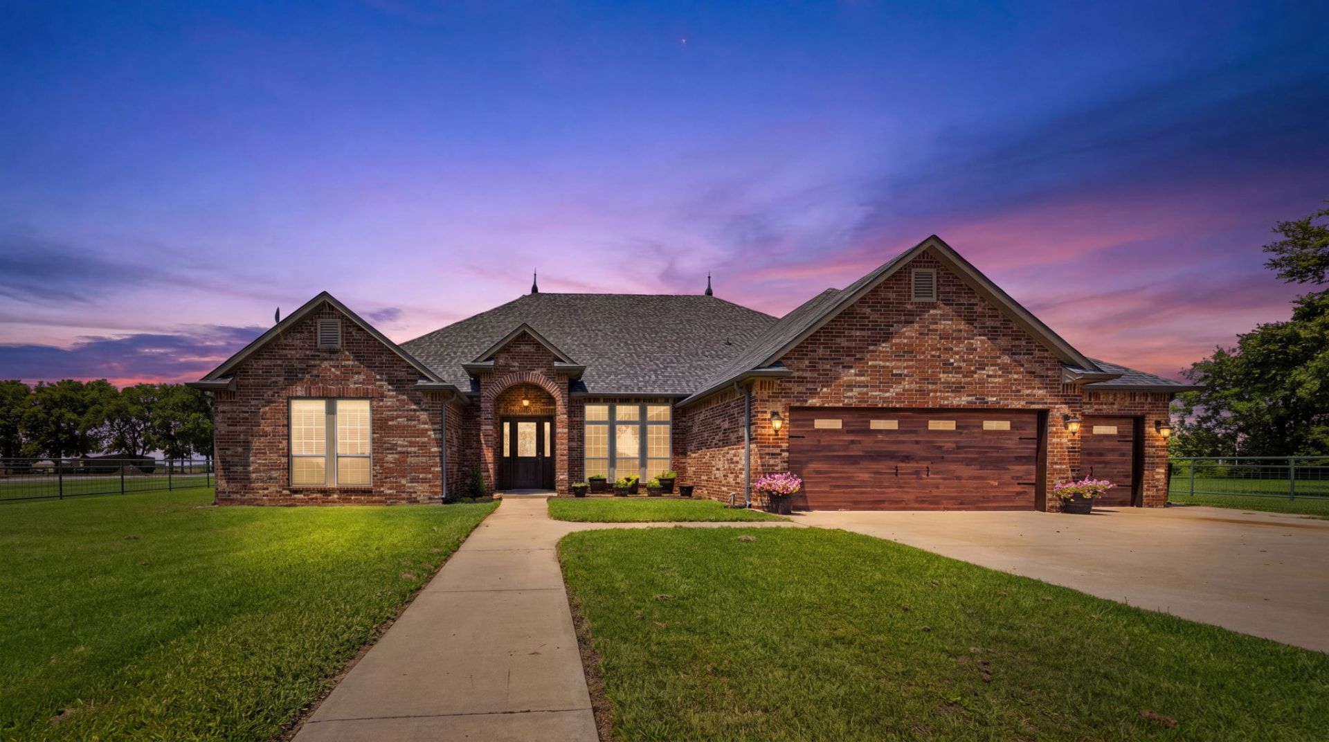 Brick home exterior illuminated at twilight — Owasso, OK