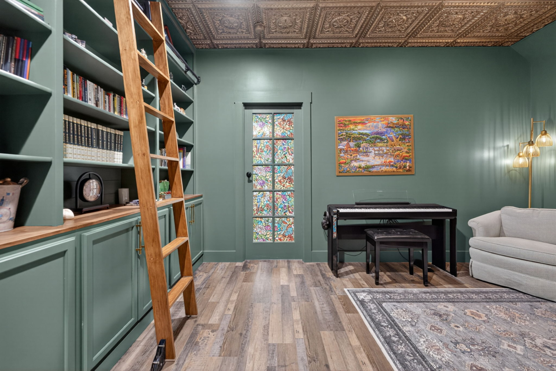 Green library with rolling ladder, built-in shelving and a pressed tin ceiling in an Owasso Oklahoma home