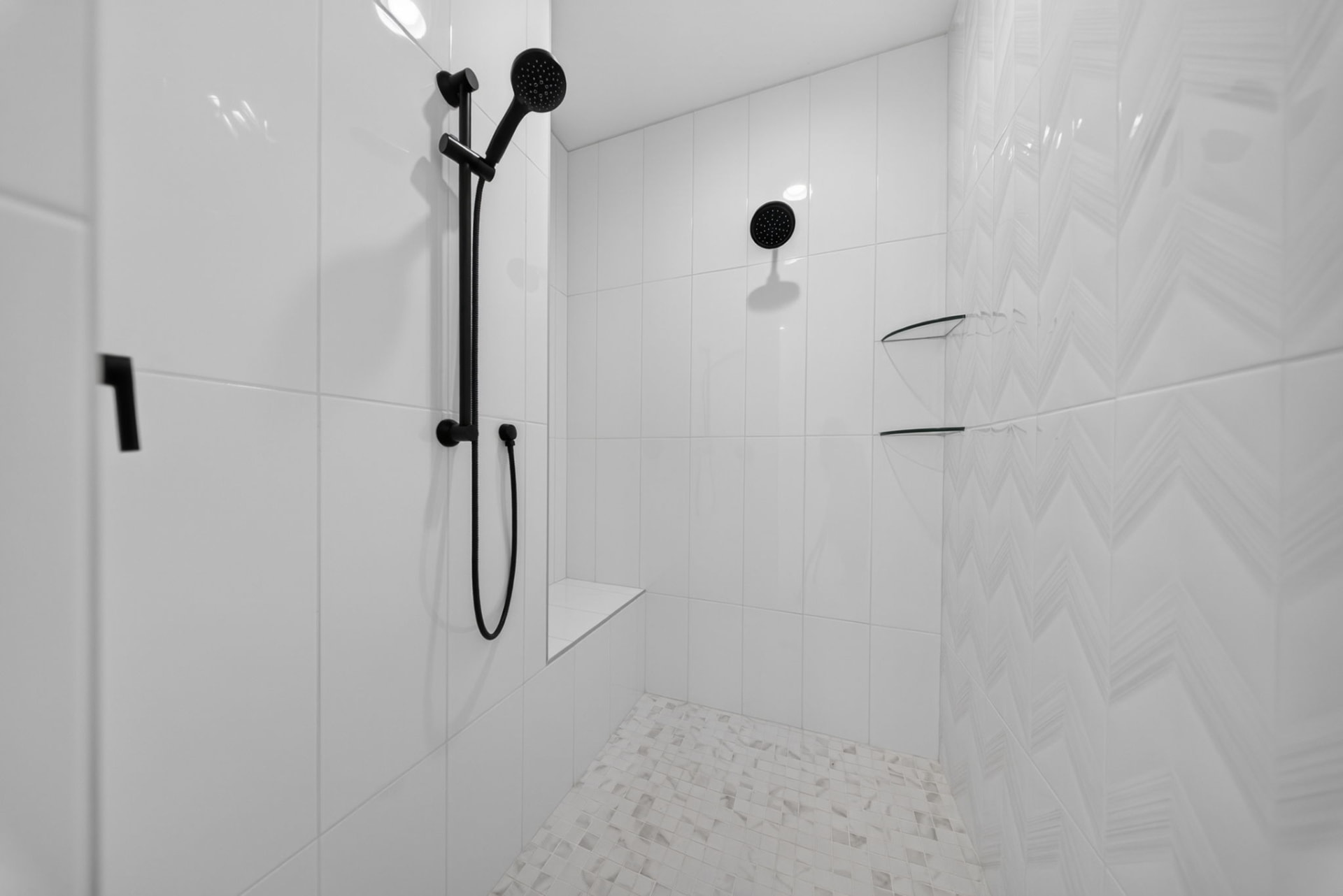 Walk-in tiled shower with matte black fixtures and herringbone accent wall in a Broken Arrow Oklahoma new build