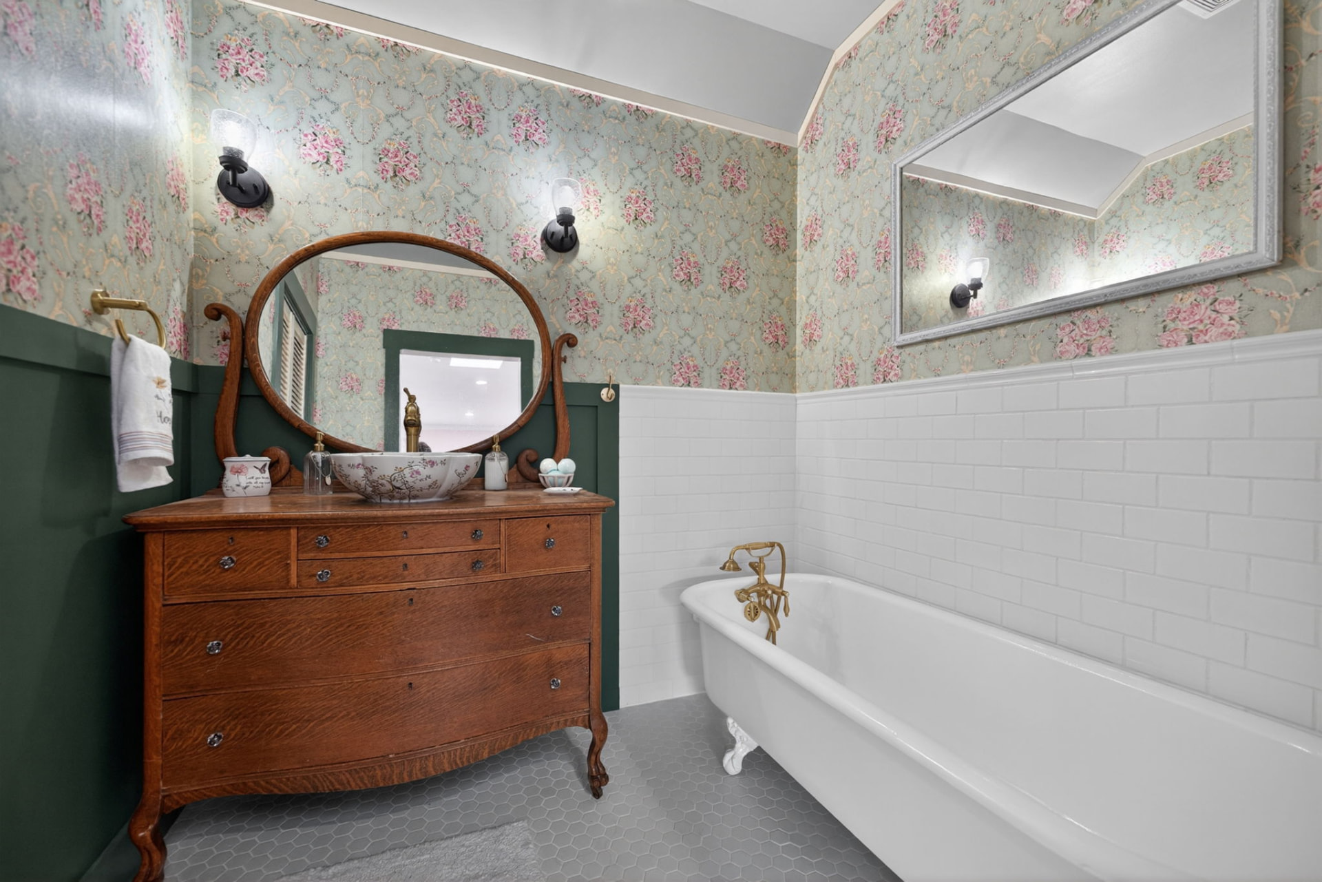Bathroom with clawfoot tub, floral wallpaper and an antique wood vanity in an Owasso Oklahoma home